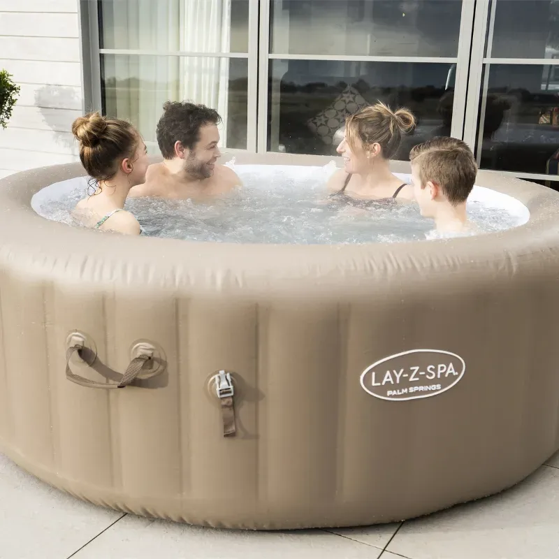 Quatre adultes assis dans le Lay-Z-Spa Palm Springs installé sur une terrasse dallée